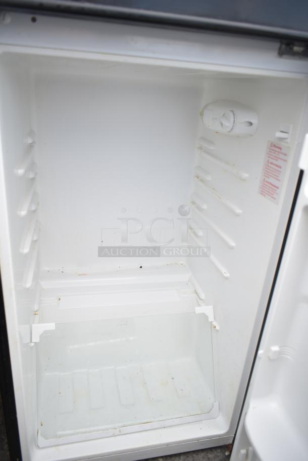 Magic Chef HMDR450BE mini cooler interior, white, clean shelves, adjustable thermostat. Includes label with safety instructions.
