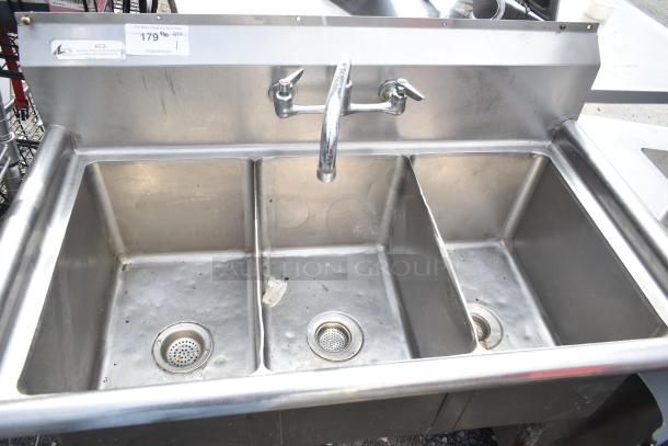 Commercial 3 bay stainless steel sink with two faucets, visible wear. Auction tag shows price $179.