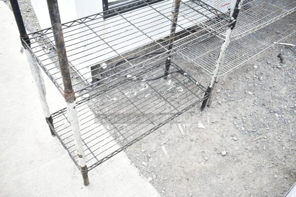 Black 4-tier wire shelving unit with signs of wear. Buyer must dismantle for shipping. Consider freight charges.