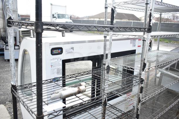 Black finish 4-tier wire shelving unit in used condition outdoors. Buyer must dismantle. Freight charges apply.