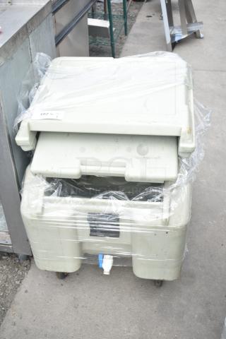 Cambro tan poly portable ice bin on commercial casters, sealed in plastic wrap, visible spout, ID label 182.