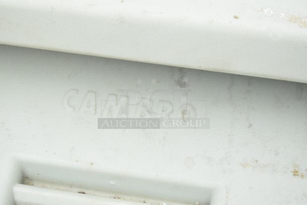 Cambro tan poly portable ice bin, embossed logo visible, shows minor wear. Equipped with commercial casters for mobility.