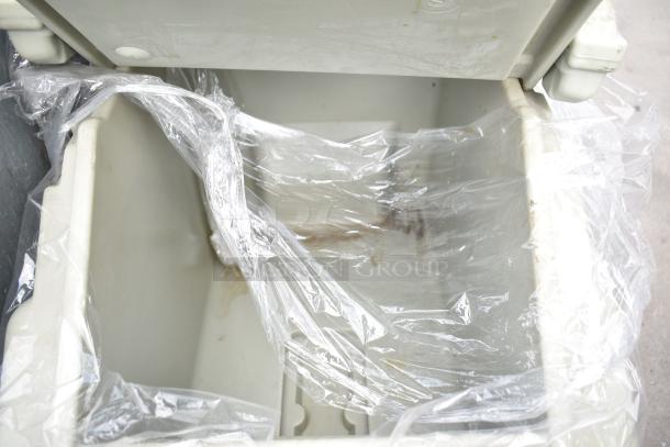 Cambro tan poly portable ice bin with lid, lined in clear plastic, on commercial casters.