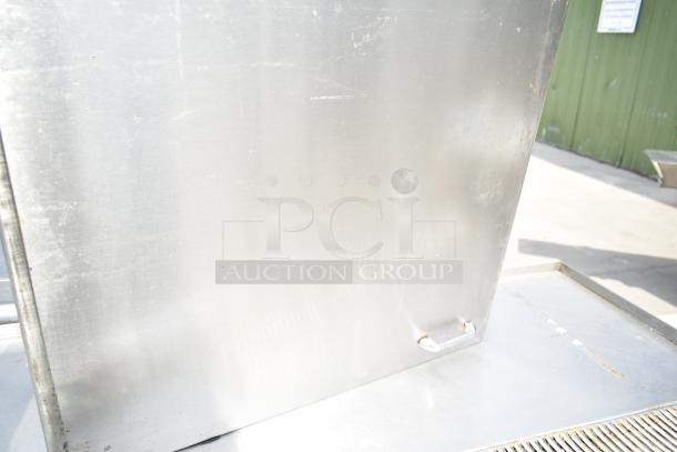 Commercial soda station with under shelves and doors, stainless steel, shows some wear, includes door handle, outdoor setting.