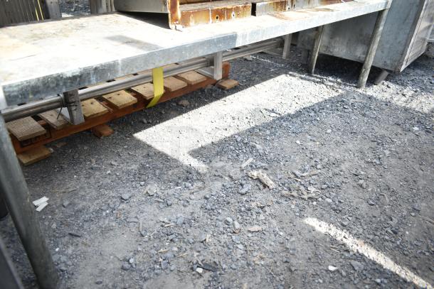 Commercial 2-tier steel overshelf with baskets, used condition, on pallets, outdoors.