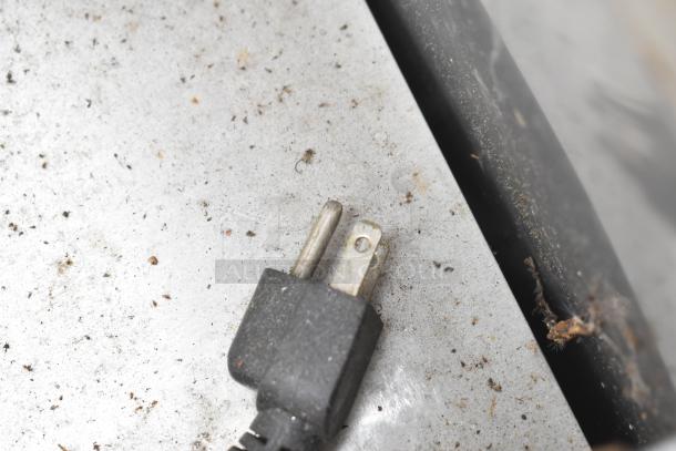 Dusty power plug of Ascend JSP-2708 prep table on metal surface, indicates electrical connection; table condition requires cleaning.