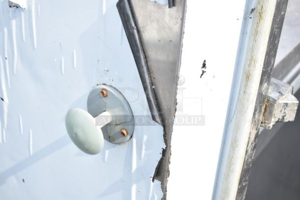 Walk-in door with metal handle, visible wear, and peeling paint, featuring a rubber seal partially detached. Ideal for DIY repair.