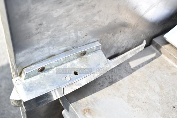 Stainless steel walk-in door hinge and latch detail, moderate wear, robust construction.