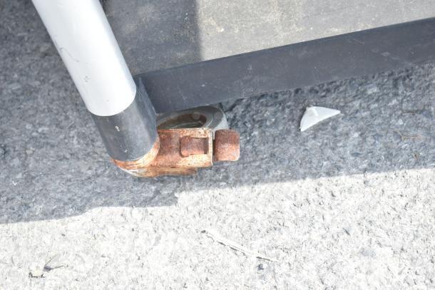 Black poly 3-tier cart with commercial casters, featuring visible wear and rust on the caster bracket.