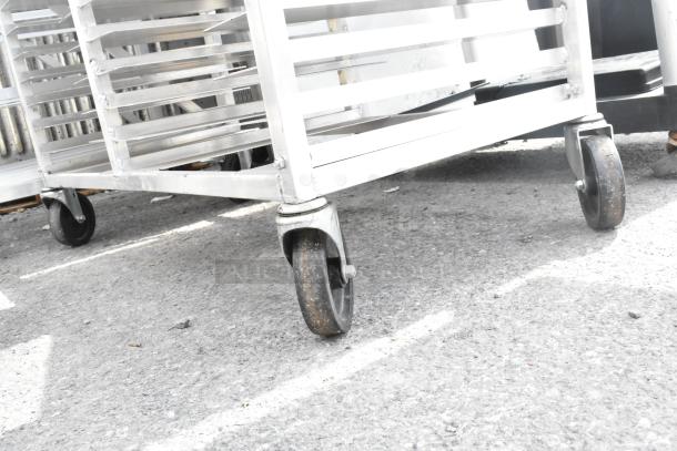 Commercial double pan transport rack with sturdy metal shelves, mounted on four heavy-duty casters, shown in used condition.