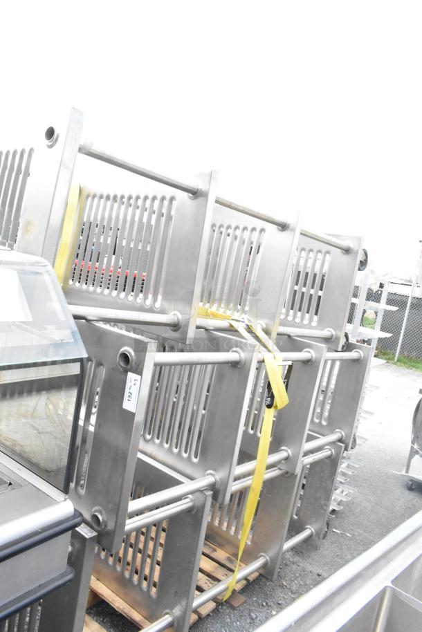 Three metal 4-tier shelving units on casters, stacked and secured with straps. Requires dismantling. Ideal for commercial use.