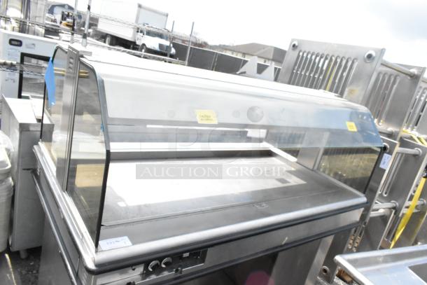 Henny Penny HMI-105 Heated Island Merchandiser, stainless steel, glass display, 120/208V, 1 Phase, visible controls, caution label.