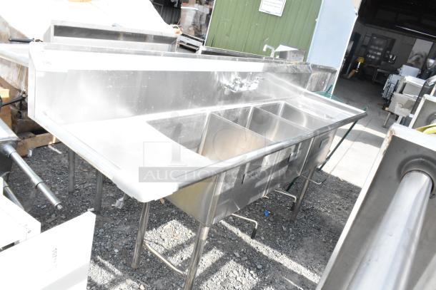 Stainless steel commercial 3 bay sink with dual drain boards, labeled "Wash." Used, in good condition.