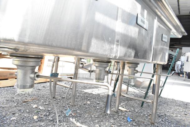 Commercial 3 bay sink with dual drain boards, stainless steel, visible signs of use, labeled rinse and sanitize.