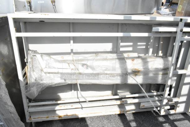 Metal panel wrapped in bubble wrap, secured within a metal frame. Slight rust visible on the frame, indicating outdoor storage.