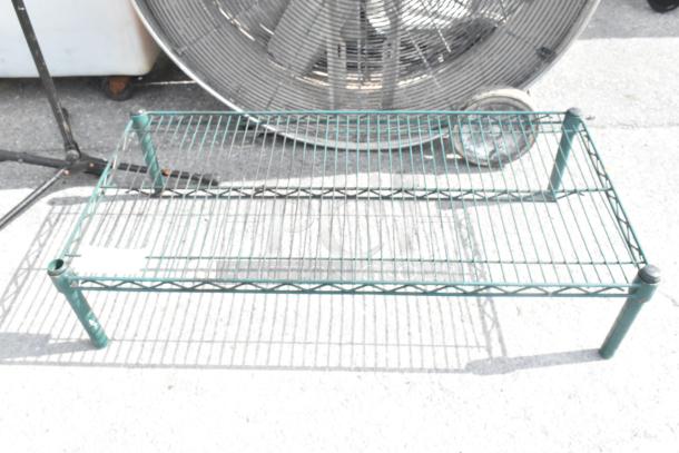 Green wire dunnage rack with slatted design, sturdy metal construction, slightly scuffed, suitable for storage.