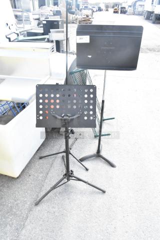 Three metal stands, including a Manhasset music stand, in used condition with adjustable features.