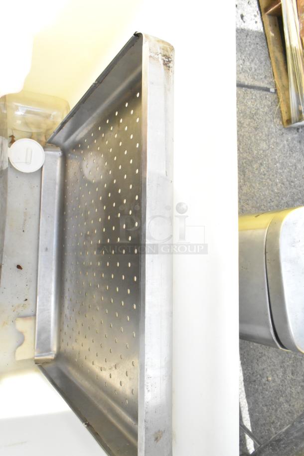 Poly trash can with contents, including a perforated metal tray and plastic container. Visible wear and signs of use.