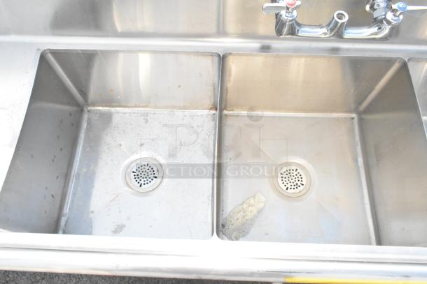 Commercial 3 bay stainless steel sink with dual drain boards, minor wear, suitable for heavy-duty kitchen use.