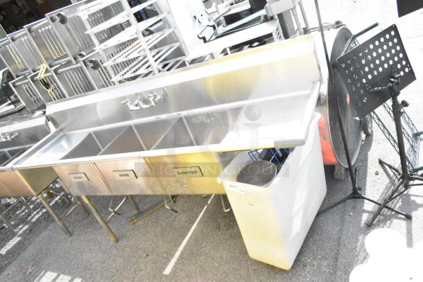 Commercial 3 bay sink with dual drain boards, labeled "Wash," "Rinse," and "Sanitize." Shows signs of use.