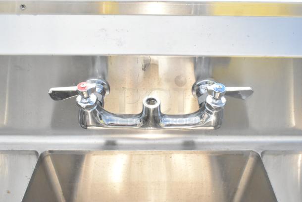 Commercial three-bay stainless steel sink with dual drain boards, featuring chrome faucets, in good condition. Ideal for kitchens.