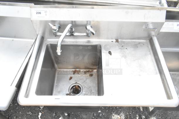 Commercial stainless steel single bay sink with right side drain board, faucet, and visible wear.