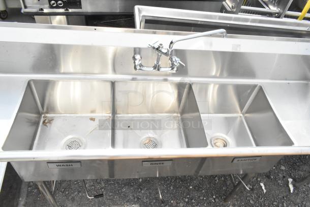 Commercial 3 bay sink with dual drain boards, stainless steel, labeled for wash, rinse, sanitize; good condition.