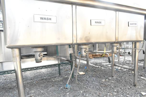 Commercial 3 bay stainless steel sink with dual drain boards, labeled Wash, Rinse, Sanitize; outdoor setting, good condition.