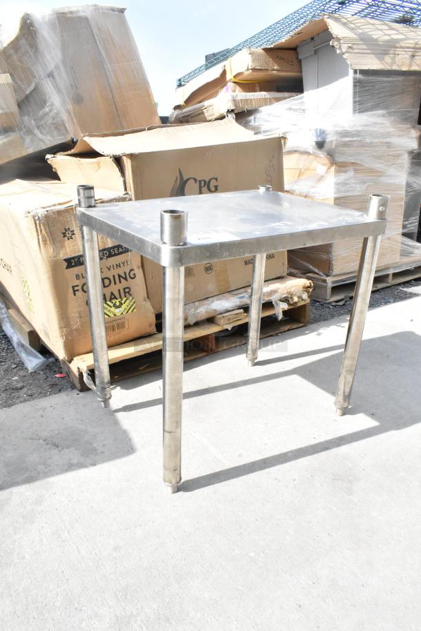Stainless steel table with four sturdy legs, industrial style, minor wear visible, suitable for workshops or garages.