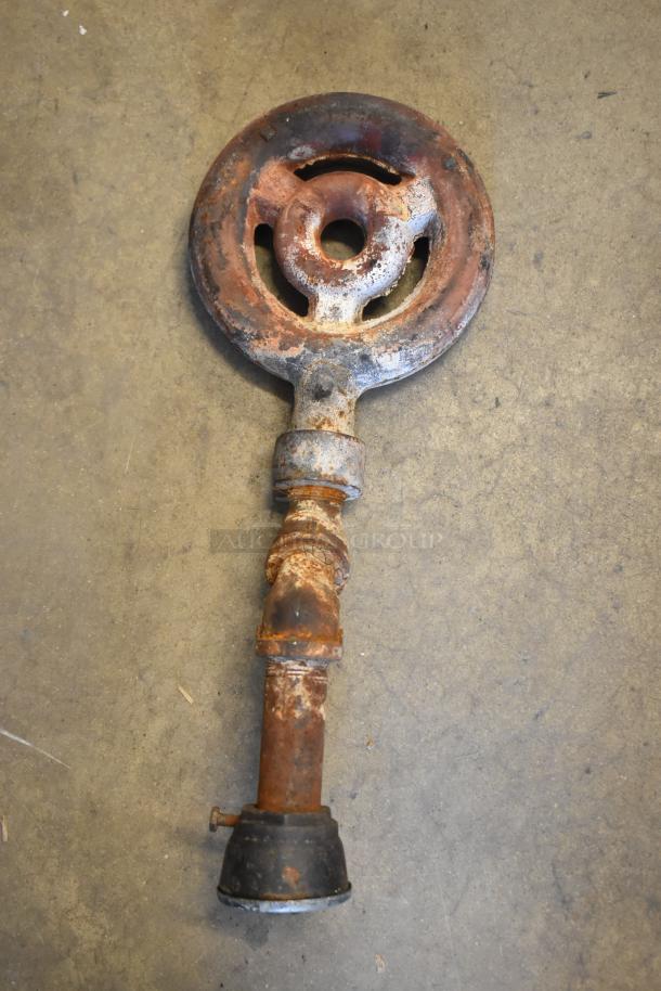 Rusty vintage stove burner head on a concrete surface, showcasing significant wear and corrosion.
