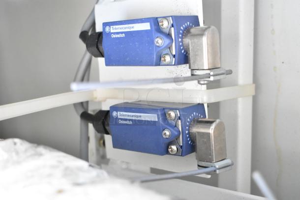 Control panel with two Telemecanique Osiswitches, blue casing, mounted on a white metal surface.