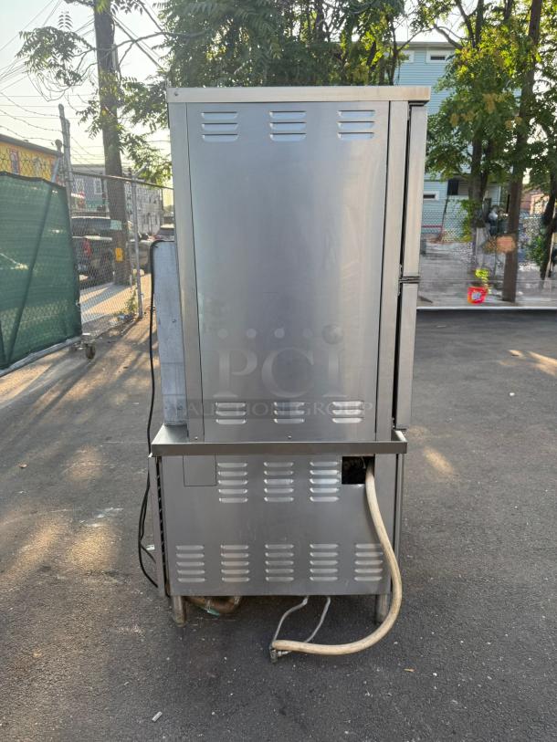 Market Forge ST-24M36G convection steamer, stainless steel, 24-pan capacity, outdoor setting, visible hose attachment.