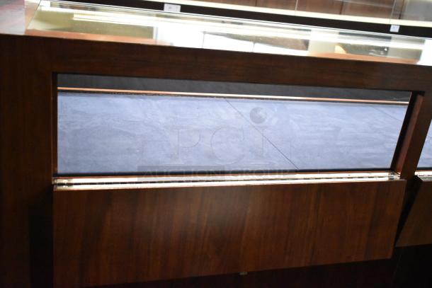 Wooden jewelry merchandising display case with a glass top and dark wood finish. Features a black velvet interior in excellent condition.