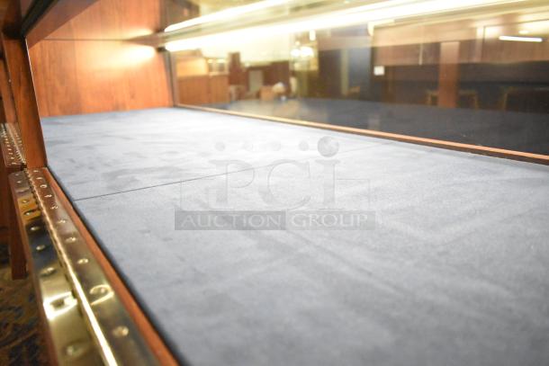 Wooden jewelry merchandising display case with glass top, blue velvet interior, and brass trim, in excellent condition.