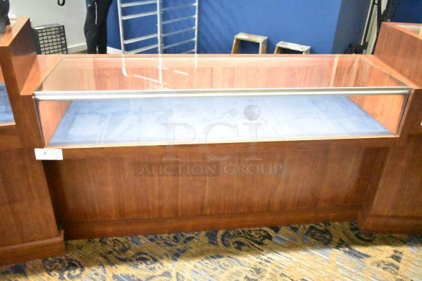 Wooden jewelry merchandising display case with glass top, wood finish, and blue interior lining. Equipped with a label indicating lot number 4.