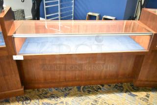 Wooden jewelry merchandising display case with glass top, wood finish, and blue interior lining. Equipped with a label indicating lot number 4.