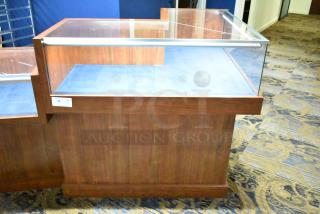 Wooden corner style jewelry display case with glass top, wooden base, and label indicating item number and quantity.
