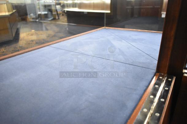 Wooden corner style jewelry merchandising display case with blue fabric surface, glass panels, and a wooden frame in good condition.