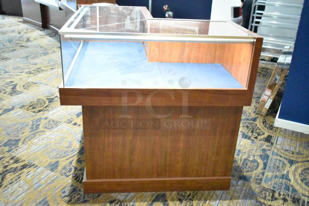 Wooden corner-style jewelry merchandising display case with glass top, light brown finish, and blue interior, in good condition.