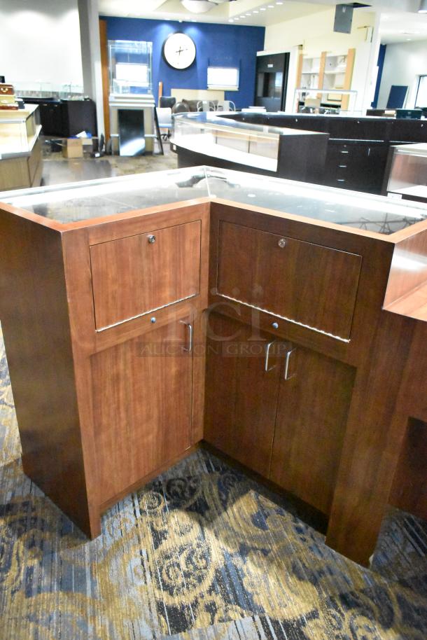 Wooden corner-style jewelry display case with glass top. Features storage cabinets below. Good condition for retail use.