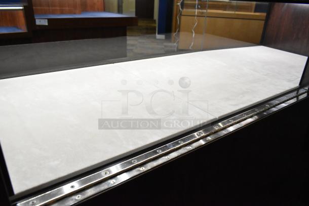 Wooden jewelry merchandising display case with glass top. Features light-colored interior and metal edge trim. Good condition.