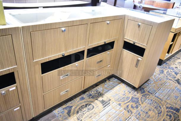 Wooden corner jewelry display case with glass tops, multiple drawers, and storage compartments. Appears in good condition.
