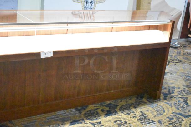 Wooden corner-style jewelry display case with two rear drawers; glass top, rich wood finish, ideal for merchandising.