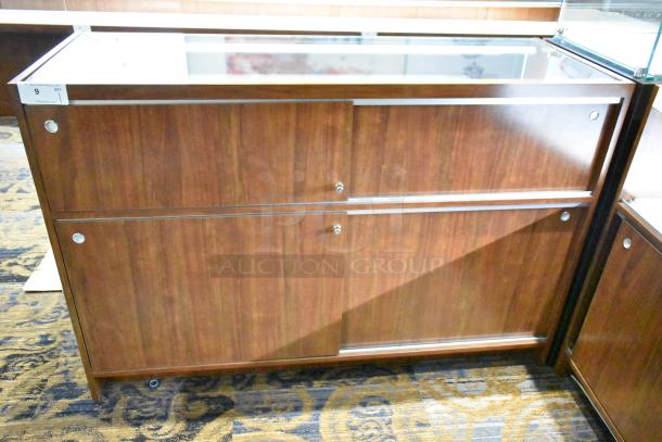 Wooden corner jewelry display case with glass top, two rear sliding doors, and rich wood finish in excellent condition.