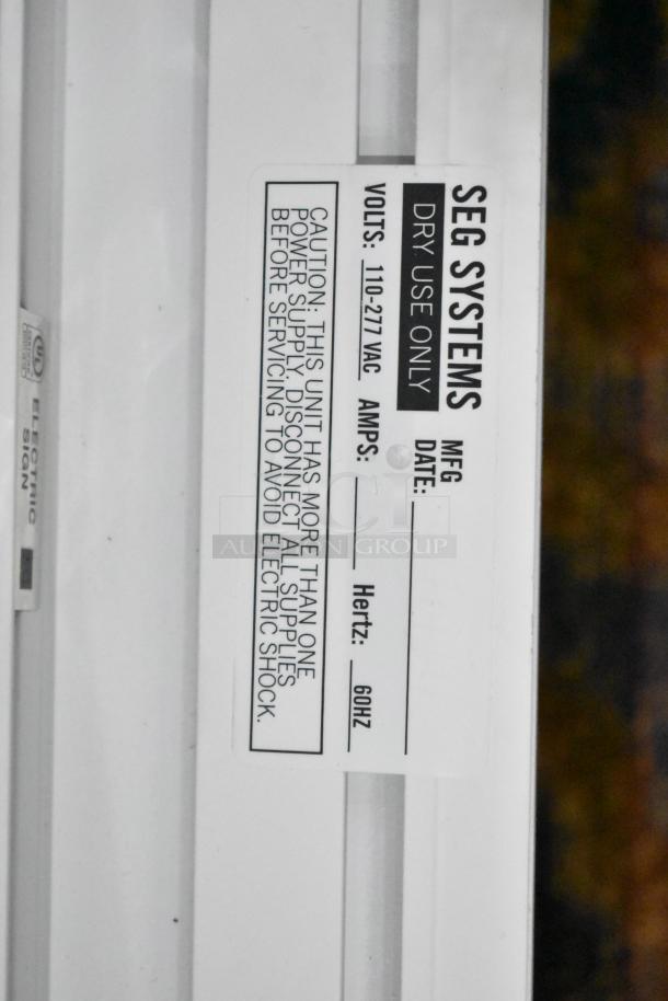 SEG Systems wall mount lighted picture frame, model LB-EDG-6D-W6-24. Voltage: 110-277 VAC. Caution label for electric safety.