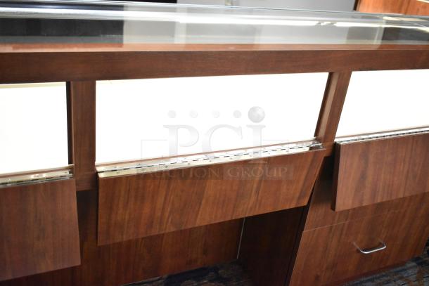 Lighted wooden jewelry merchandising display case with glass top, two drawers, and elegant finish, in good condition.