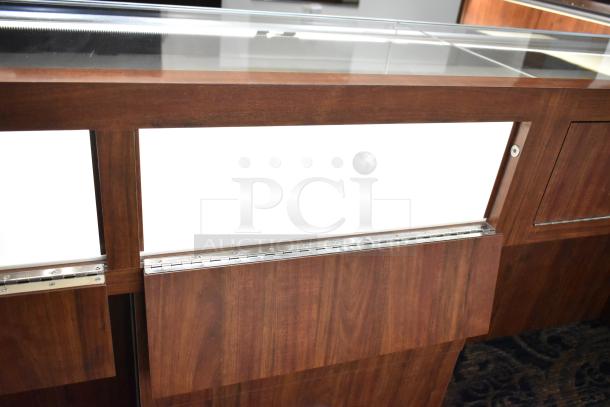 Lighted wooden jewelry display case with glass top and two drawers, showcasing a rich wood finish and modern design for retail use.