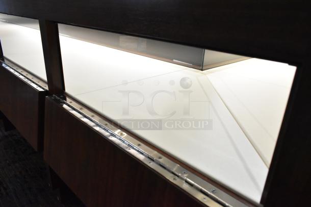 Lighted wooden jewelry merchandising display case, features glass paneling and interior lighting; excellent condition.