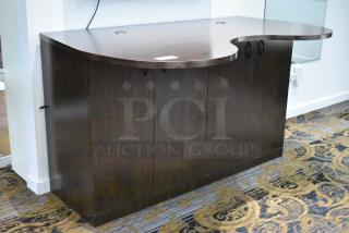 Dark wooden counter with a wavy top, featuring four doors. Sleek design, good condition, ideal for storage and display.
