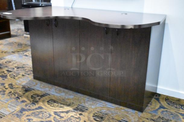 Wooden counter with wavy top and four doors, dark finish, in good condition. Ideal for office or retail use.